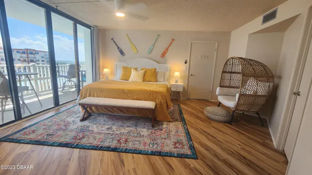a bedroom with a bed a mirror on dresser with wooden floor