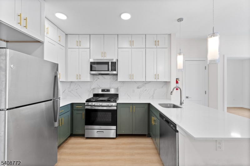 321 East 3rd Street, Unit 320 Plainfield, NJ 07060 - Photo 25 of 43 a kitchen with stainless steel appliances a stove a sink a refrigerator a window and white cabinets