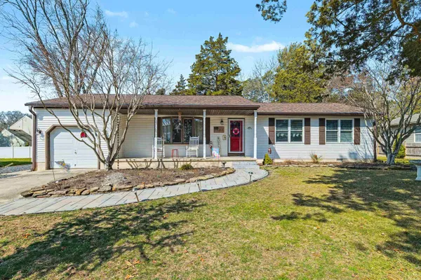 a view of a white house with a large tree and wooden fence