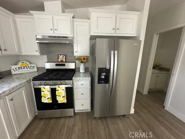 a kitchen with stainless steel appliances a refrigerator a stove a sink and wooden floors