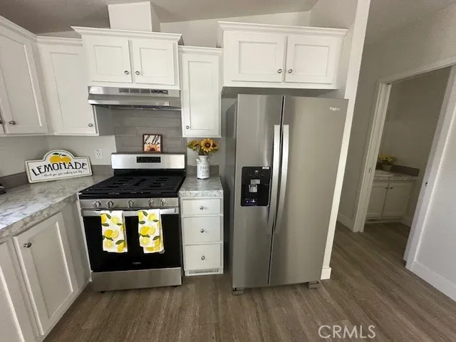 a kitchen with stainless steel appliances a refrigerator a stove a sink and wooden floors