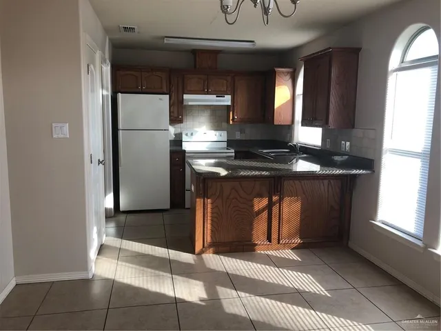 a kitchen with kitchen island granite countertop a refrigerator a sink and a stove