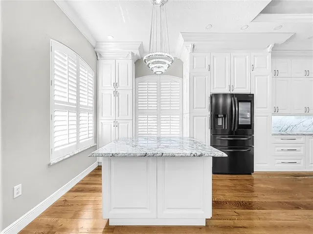 a kitchen with granite countertop a refrigerator and a stove top oven