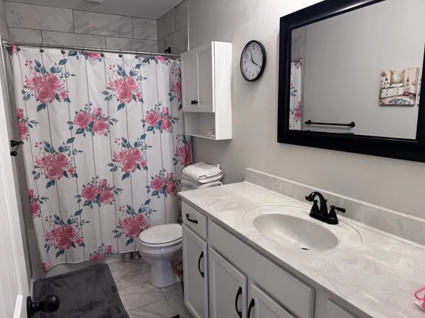 an empty room with chandelier fan and windows