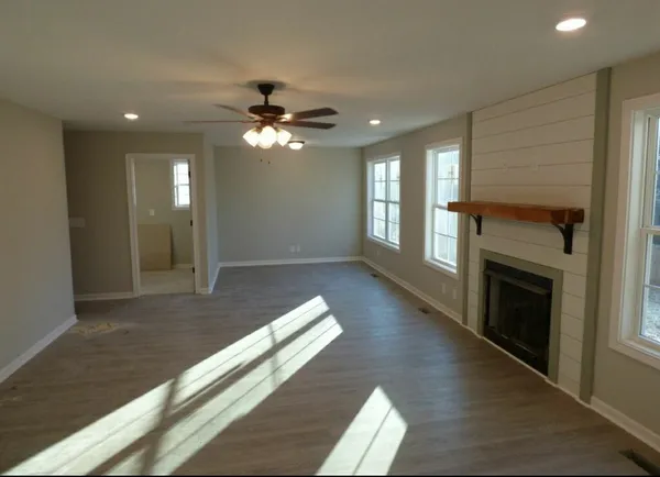 an empty room with wooden floor fireplace and windows