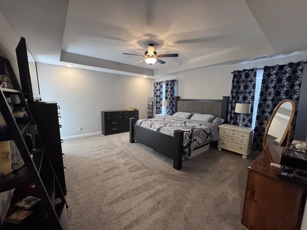 a bedroom with a bed a couch and a flat tv screen on the dresser