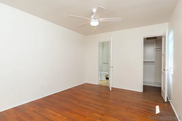 a view of empty room with wooden floor and ceiling fan