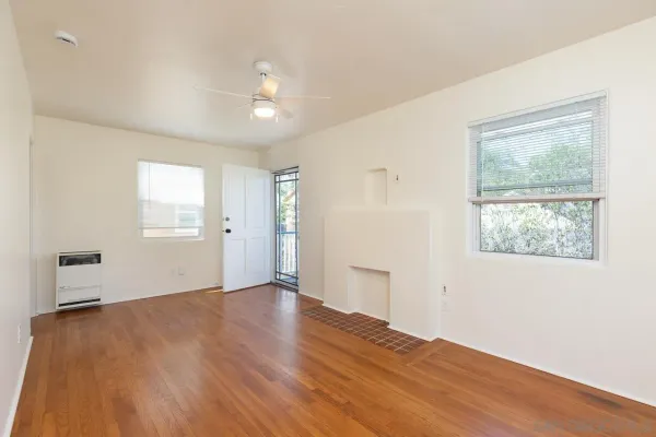 a view of an empty room with wooden floor and a window