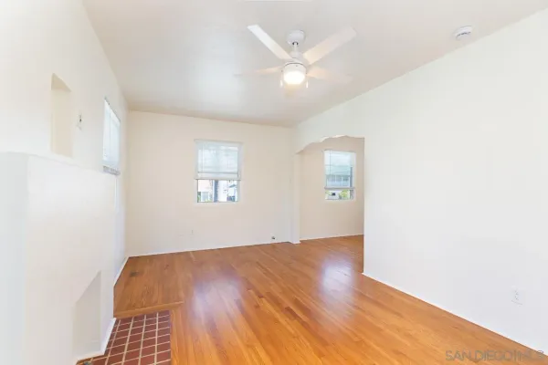 an empty room with wooden floor closet and windows