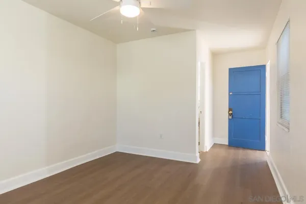 an empty room with wooden floor and fan