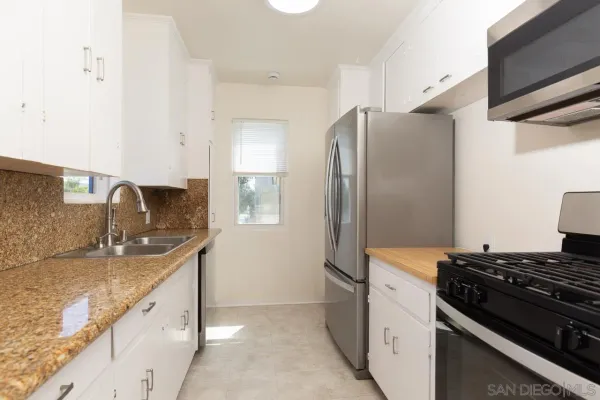 a kitchen with granite countertop a sink stove and refrigerator