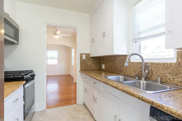 a kitchen with granite countertop a sink a stove and cabinets