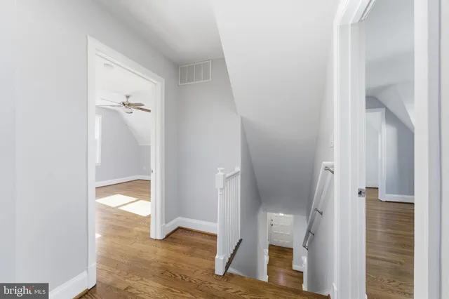 a view of empty room with wooden floor and fan