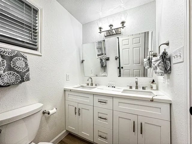 a bathroom with a double vanity sink toilet and mirror