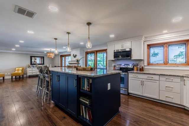 a kitchen with stainless steel appliances granite countertop wooden cabinets a sink a stove a dining table and chairs