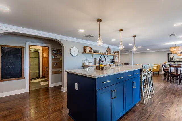 a kitchen with stainless steel appliances granite countertop wooden floors and a view of living room