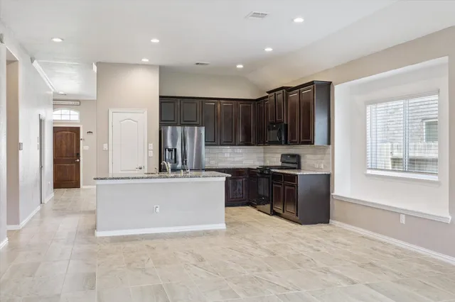 a large kitchen with stainless steel appliances granite countertop a stove refrigerator and a sink