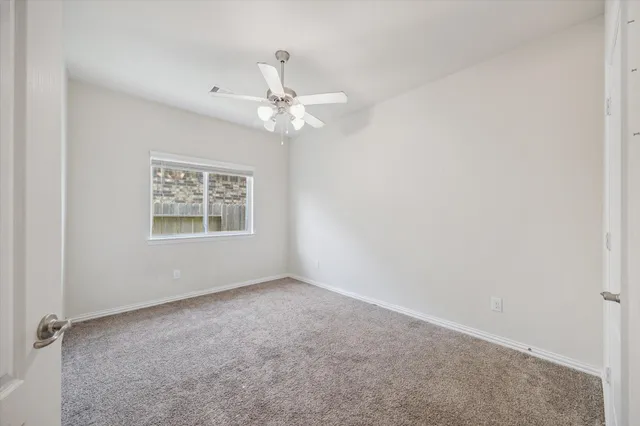an empty room with a window and a ceiling fan
