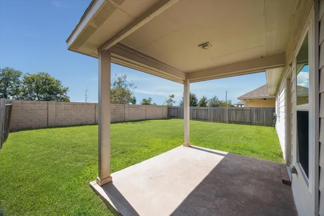 a view of a backyard with grass & a fence