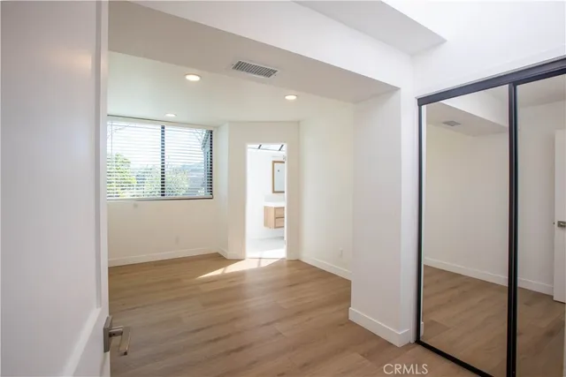 a view of an empty room with wooden floor and closet