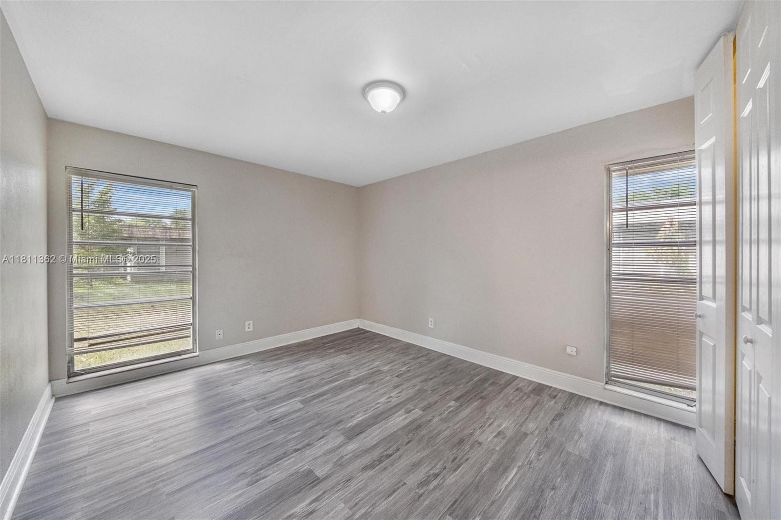 7019 Northwest 63rd Street Tamarac, FL 33321 - Photo 11 of 33 an empty room with wooden floor and windows