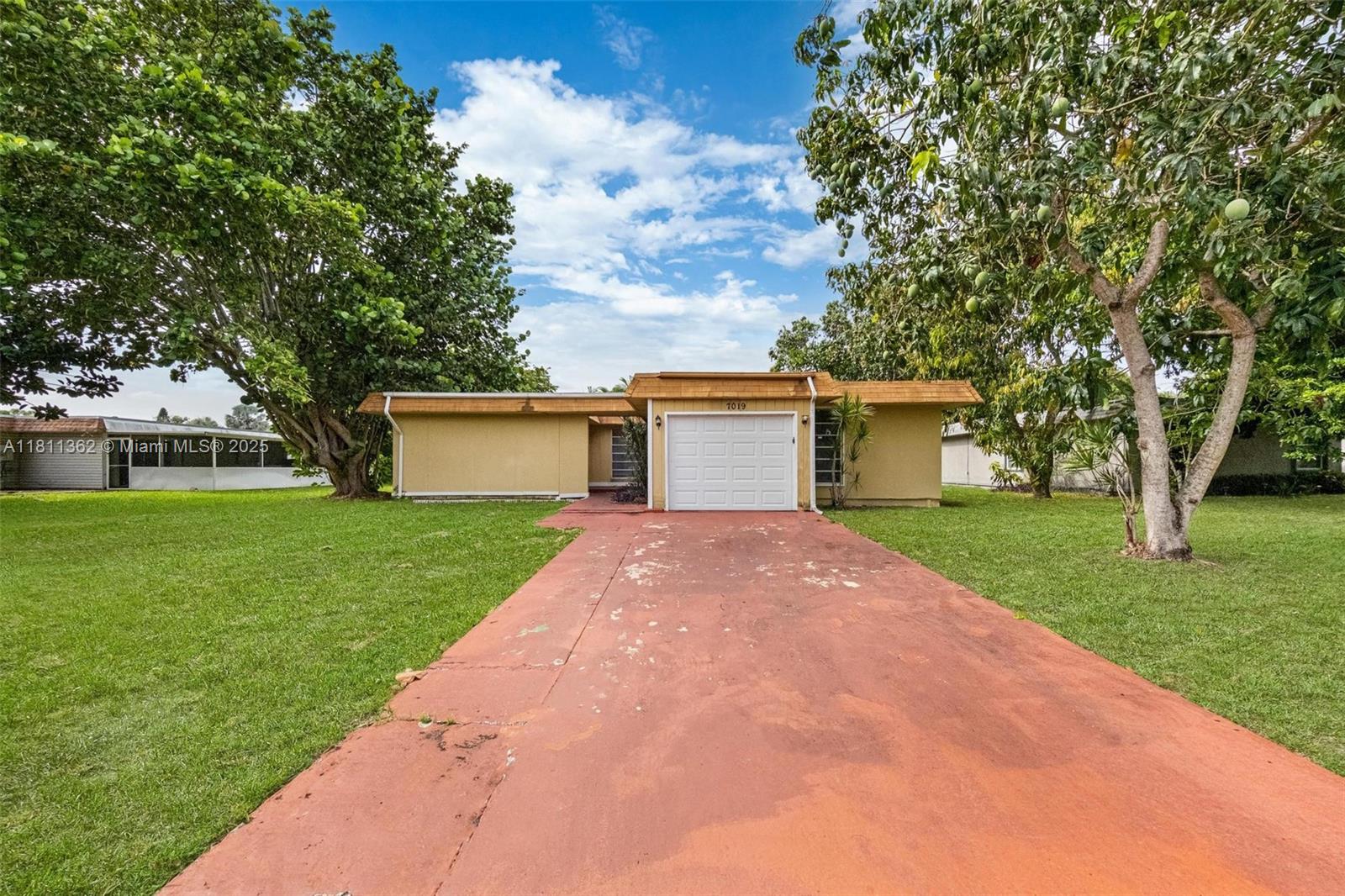 7019 Northwest 63rd Street Tamarac, FL 33321 - Photo 26 of 33 a front view of a house with a yard and trees