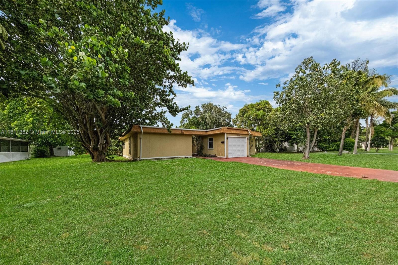 7019 Northwest 63rd Street Tamarac, FL 33321 - Photo 4 of 33 a front view of a house with a yard and trees