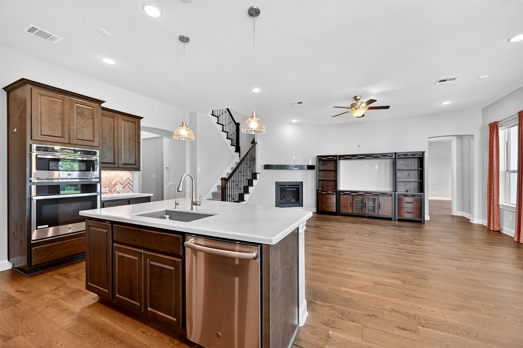 1201 Positano Pass Leander, TX 78641 - Photo 13 of 40 Kitchen island with sink, stainless steel appliances, dark wood cabinetry, white countertops, and wood-finish flooring