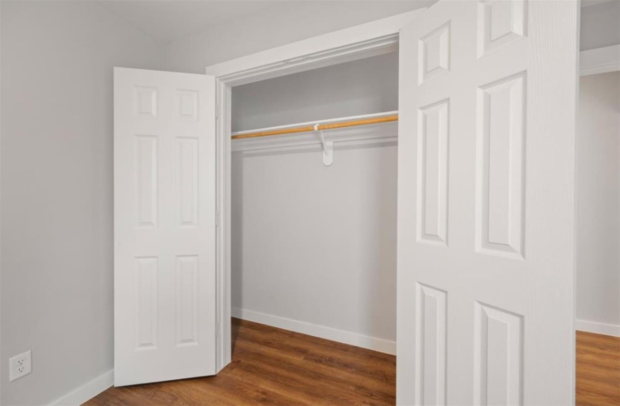 8120 Laura Koppe Road, Unit B Houston, TX 77028 - Photo 14 of 25 This photo shows a clean, empty closet with white bifold doors, a wooden rod for hanging clothes, and a laminate wood floor, perfect for storage and organization.