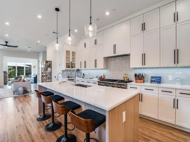 a kitchen with a stove a sink a kitchen island and chairs with wooden floor