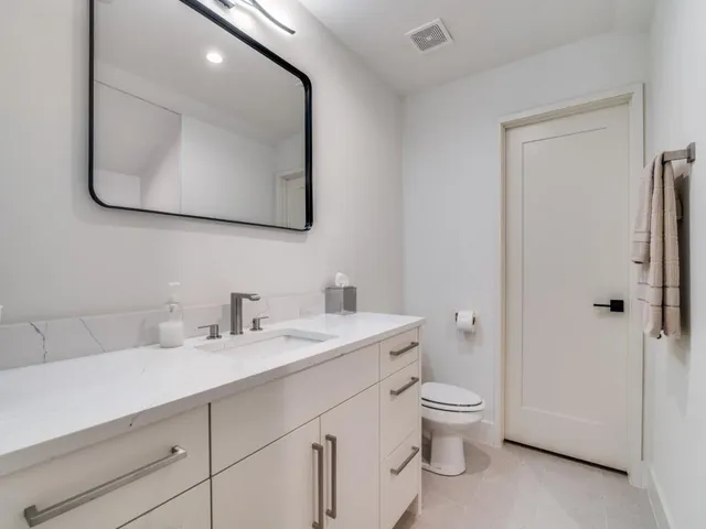 a bathroom with a toilet a sink a mirror and vanity