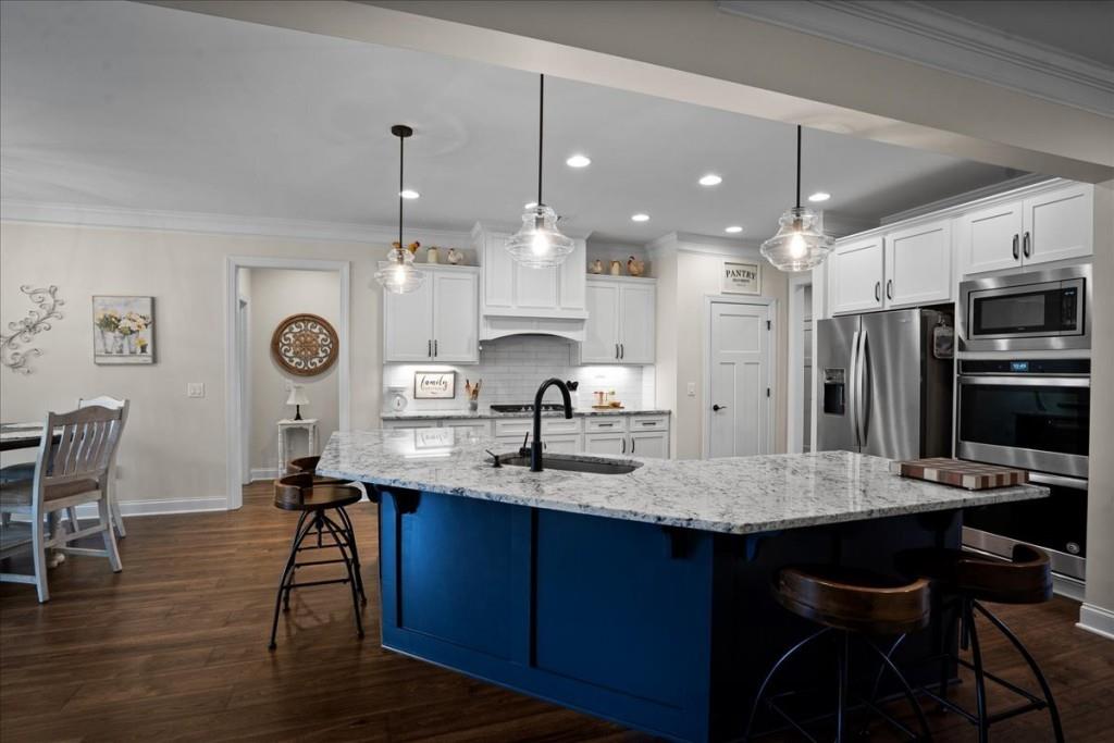641 Haven Way Monroe, GA 30655 - Photo 6 of 55 a kitchen with kitchen island granite countertop a table chairs refrigerator and cabinets
