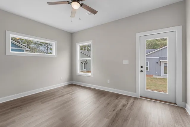 a view of an empty room with a window and wooden floor