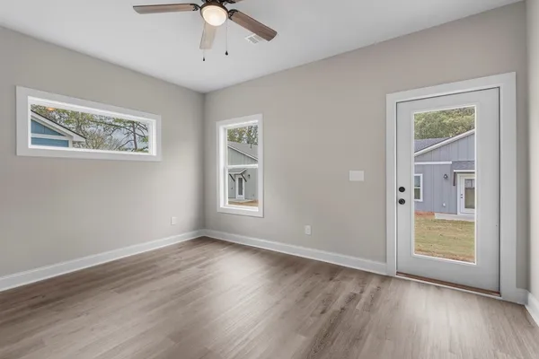 a view of an empty room with a window and wooden floor