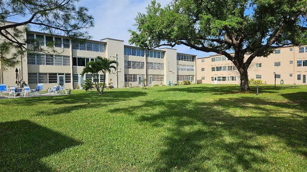 4600 98th Way North, Unit 210 St. Petersburg, FL 33708 - Photo 2 of 33 a view of a house with a big yard and large trees