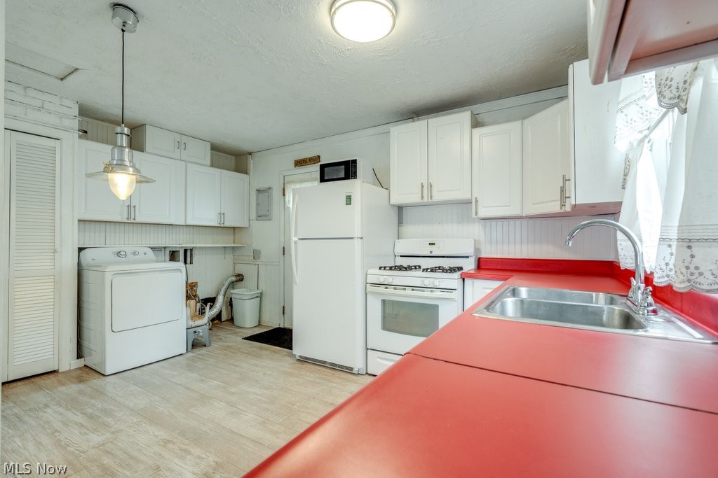 2712 Ridge Road Warren, OH 44484 - Photo 11 of 27 Kitchen with washer / dryer, white appliances, light wood-type flooring, white cabinets, and a textured ceiling