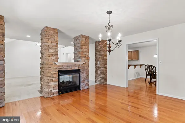 a view of a livingroom with a fireplace a chandelier and wooden floor