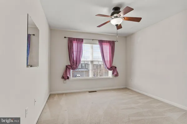 a view of an empty room and chandelier fan