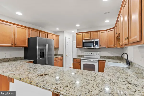 a kitchen with stainless steel appliances granite countertop a refrigerator sink and stove