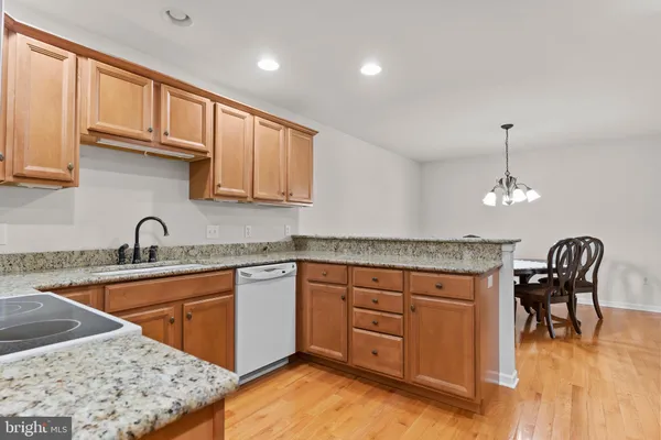 a kitchen with stainless steel appliances granite countertop a sink a stove a dining table and chairs with wooden floor
