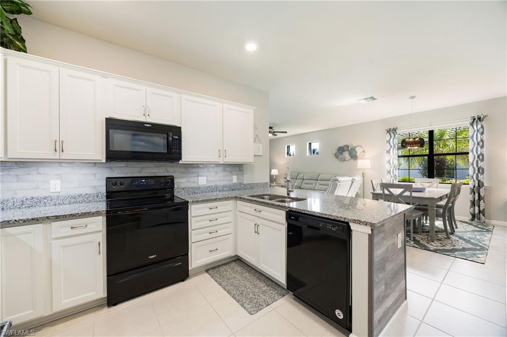 6125 Triumph Lane Ave Maria, FL 34142 - Photo 11 of 31 Kitchen featuring black appliances, light stone countertops, white cabinets, a peninsula, and light tile patterned flooring