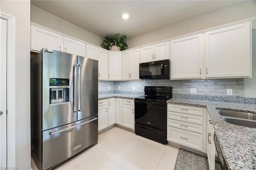6125 Triumph Lane Ave Maria, FL 34142 - Photo 12 of 31 Kitchen featuring black appliances, light stone counters, white cabinetry, backsplash, and recessed lighting