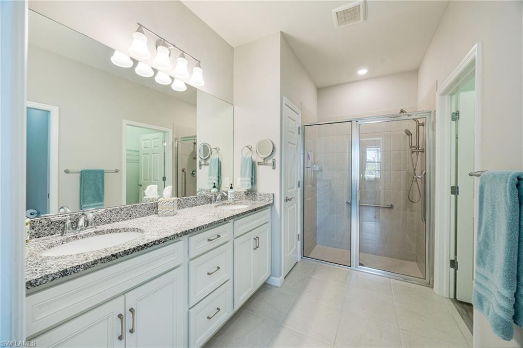 6125 Triumph Lane Ave Maria, FL 34142 - Photo 25 of 45 a spacious bathroom with a granite countertop sink a mirror and a shower