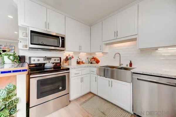 a kitchen with white cabinets stainless steel appliances and sink