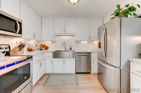 a kitchen with stainless steel appliances a refrigerator sink and white cabinets