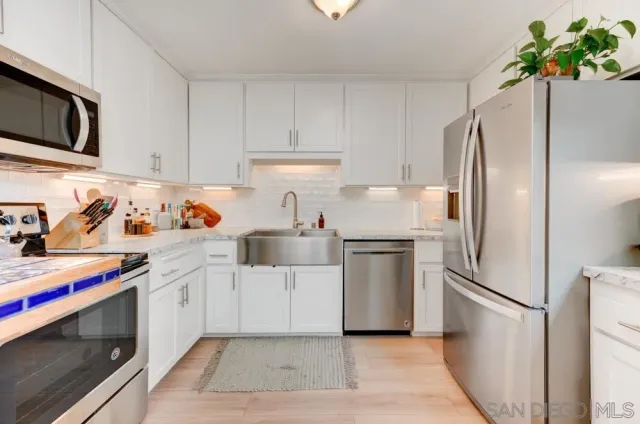 a kitchen with stainless steel appliances a refrigerator sink and white cabinets