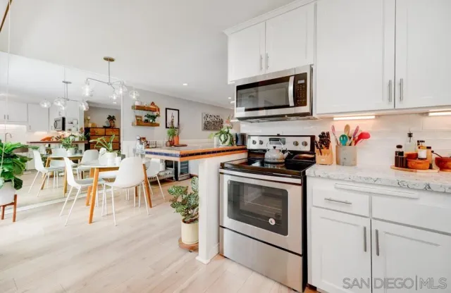 a kitchen with stainless steel appliances granite countertop a stove top oven a sink dishwasher and white cabinets with wooden floor