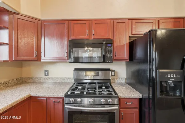 a kitchen with granite countertop a stove sink and refrigerator