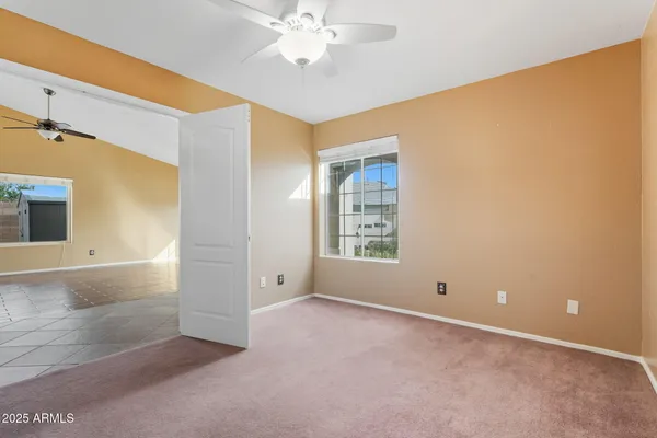 an empty room with windows and fan