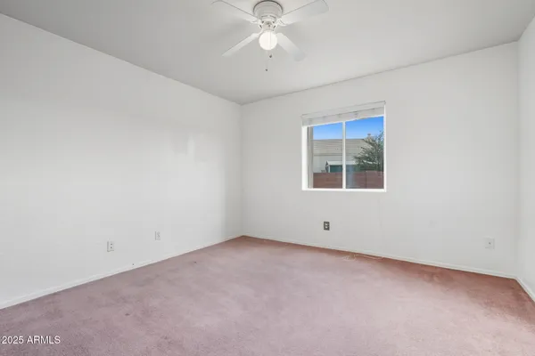 an empty room with a window and a fan